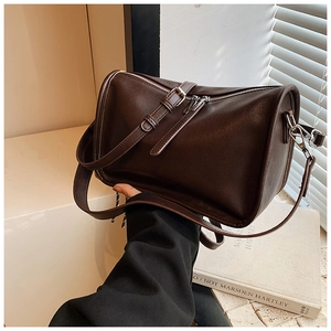 Detail of dark brown faux leather Boston bag with silver zipper and decorative belt strap