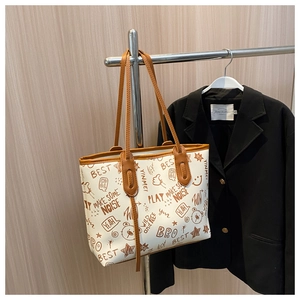 Detail der weißen Tragetasche mit Graffiti-Print, hängend neben einem schwarzen Blazer