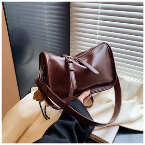 Detail of vintage brown leather handbag with zipper and a cute animal charm
