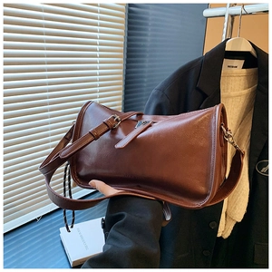 Detail showing the brown vintage oil wax leather texture and adjustable strap on the bag