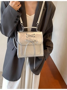 Silver metallic mini backpack with bow tassel and cylindrical handle for casual wear