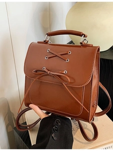 Brown faux leather backpack with lace-up bow detail and top handle in a vintage style