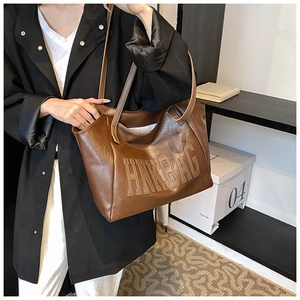 Dettaglio macro della borsa tote vintage marrone con lettere HNK goffrate e trama in pelle