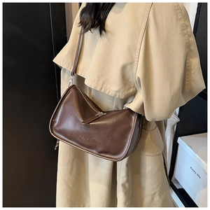 Detailed view of coffee brown crossbody bag with matte leather finish and brand embossing
