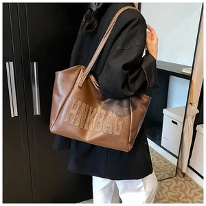 Dettaglio di una grande borsa tote marrone con logo HNKBAG in rilievo su pelle PU