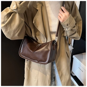 Detail of dark brown faux leather pillow bag with adjustable strap and metal zipper