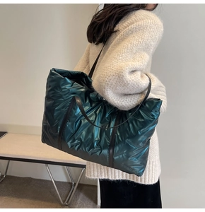 Détail d'un grand sac cabas matelassé vert foncé avec poignées en cuir noir et effet brillant