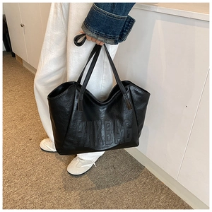 Dettaglio della borsa tote nera con scritte HMKBAG in rilievo e trama in pelle lucida