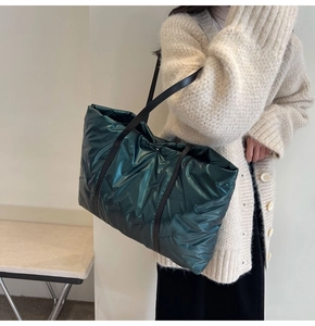 Gros plan d'un sac cabas matelassé vert foncé avec une finition brillante et bandoulière