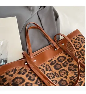 Gros plan sur le sac cabas léopard avec bordure en cuir marron et détails de rivets