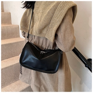 Detail of vintage black leather handbag featuring a silver zipper and checkered charm strap