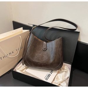 Detailed close-up of dark brown leather bucket bag with contrasting white stitching in a gift box
