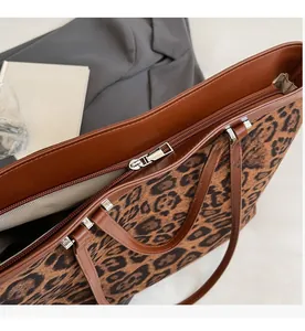 Détail du sac cabas léopard avec bordure en cuir marron et fermeture éclair argentée