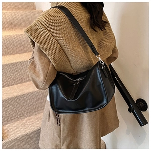 Close-up of black leather half-moon bag with adjustable strap and silver metal hooks