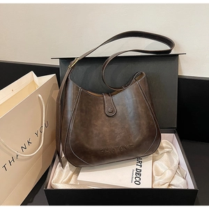 Close-up of retro brown shoulder bag with contrast stitching in a premium gift box set