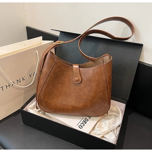 Detailed shot of brown vintage leather bucket bag with white stitching in premium gift box