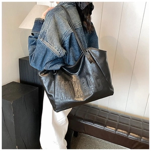 Dettaglio borsa tote nera in ecopelle con scritta HMK BAG in rilievo e trama vintage