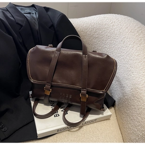 Dettaglio dello zaino vintage in pelle PU marrone scuro con fibbie dorate su un libro