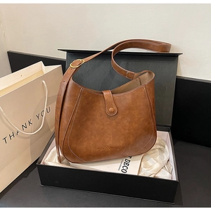 Detailed view of brown vintage leather saddle bag with contrast stitching and gold buckle