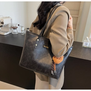 Detailansicht der schwarzen Leder-Shopper mit Goldnieten und braunem Pelzanhänger
