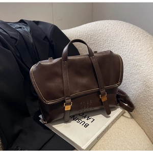 Dettaglio borsa a mano vintage marrone scuro con scritte impresse e fibbia metallica lucida