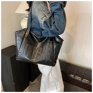 Dettaglio del logo HNKBAG goffrato su una grande borsa tote nera in ecopelle da donna