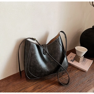 Detail of dark grey retro leather hobo bag featuring white contrast stitching and snap buckle