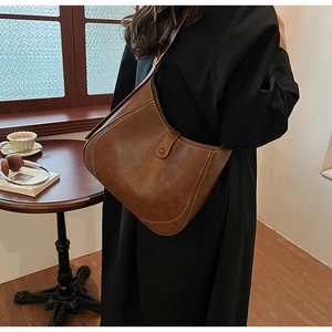 Detail of vintage brown leather bucket bag with white contrast stitching and metal rings