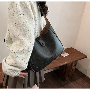 Detailed close-up of dark grey retro hobo bag with contrast stitching and embossed logo