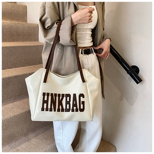 Dettaglio della borsa tote crema con stampa HNKBAG marrone e sottili tracolle in pelle