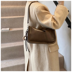 Close-up of a brown baguette bag with a decorative round pendant and striped knot detail