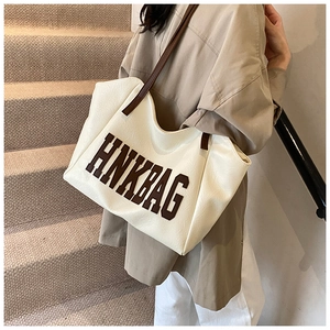 Dettaglio della borsa tote crema alla moda con scritte HNK BAG marroni per uso quotidiano