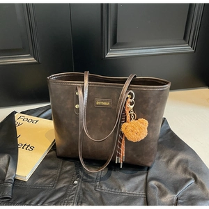 Detailansicht einer dunkelbraunen Tote-Tasche mit Vintage-Lederstruktur und Bärenanhänger