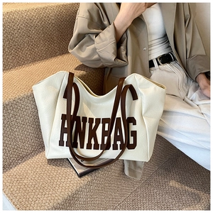 Dettaglio di una grande borsa tote crema con manici marroni e logo ANKBAG
