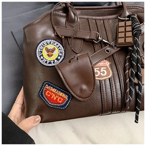 Nahaufnahme der braunen Retro-Tasche mit Vintage-Stickereien und Schokoladenanhänger