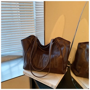 Dettaglio di una grande borsa tote marrone vintage con testo pinkbag goffrato su un libro