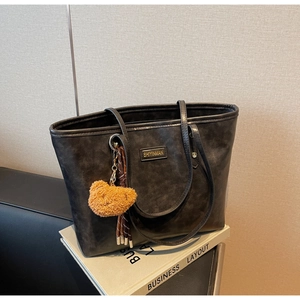 Detail der schwarzen Shopper-Tasche mit Teddybär-Anhänger und goldenem Logo