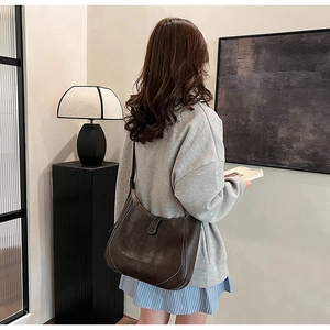 Detail of dark brown leather shoulder bag featuring vintage texture and fine stitching