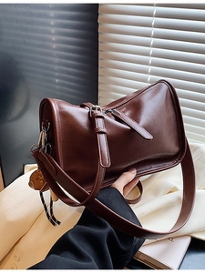 Vintage brown leather shoulder bag for women with adjustable strap in natural lighting