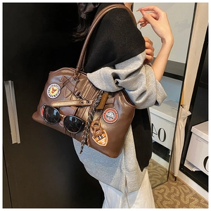Nahaufnahme der braunen Retro-Tasche mit Stickereiaufnähern und Sonnenbrillen-Halterung