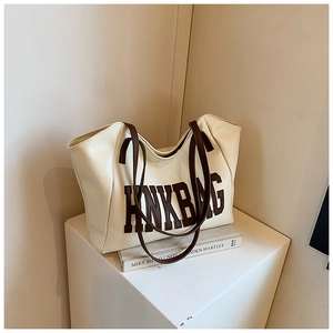 Vista dettagliata della borsa tote in pelle color crema con scritta HNKBAG marrone