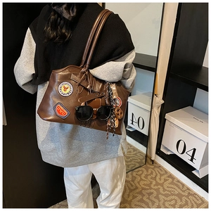 Detail der braunen Vintage-PU-Ledertasche mit Retro-Stickabzeichen und Seidenschal-Zubehör