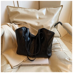 Dettaglio della borsa tote in pelle nera con goffratura HIKBAG su seduta bianca