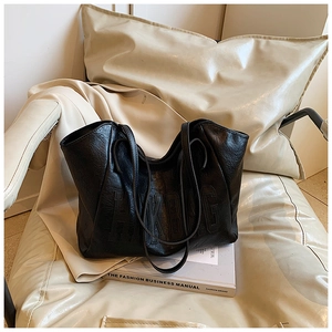 Dettaglio della borsa tote nera con trama pieghettata e scritte HKBAG goffrate sulla pelle