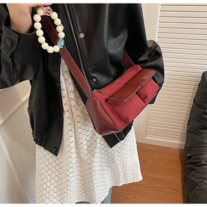 Model wearing a burgundy suede baguette crossbody bag with dual front flap pockets