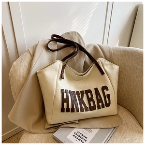 Dettaglio della borsa tote bianco sporco con logo HNKBAG marrone scuro e spalline sottili
