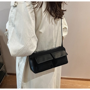 Detailed view of a black matte suede baguette bag with dual pockets on a female model