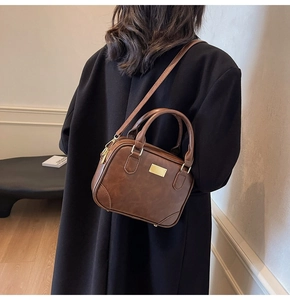 Detail view of retro brown crossbody bag with gold hardware and fine stitching on a model