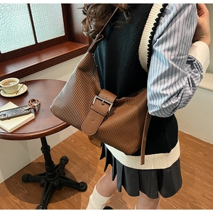 Close-up of brown textured crossbody bag with oversized silver metal buckle detail