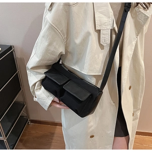 Detail shot of a black workwear-style crossbody bag with double front flap pockets